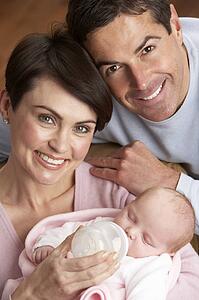 Portrait Of Parents Feeding Newborn Baby At Home