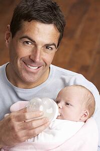 Portrait Of Father Feeding Newborn Baby At Home