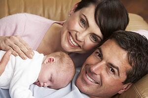 Portrait Of Proud Parents With Newborn Baby At Home