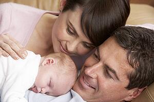 Portrait Of Proud Parents With Newborn Baby At Home