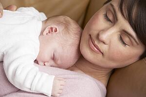 Portrait Of Mother Resting With Newborn Baby At Home