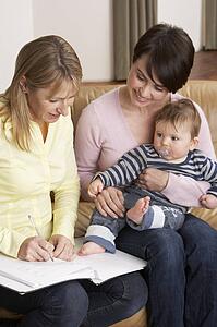 Mother With Baby Talking With Health Visitor At Home
