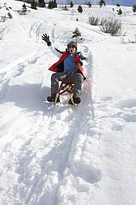 Pre-teen Boy On A Sled In The Snow