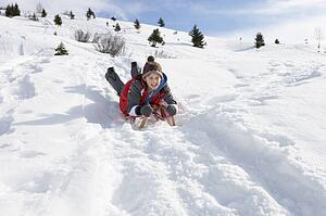 Pre-teen Boy On A Sled In The Snow