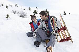 Young Father And Son In Snow With Sled
