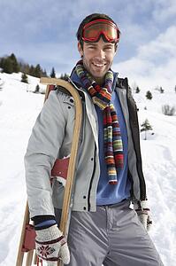 Young Man Carrying Sled In Alpine Landscape
