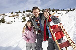 Young Father And Children In Snow With Sled