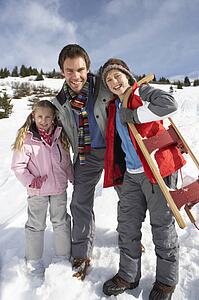 Young Father And Children In Snow With Sled