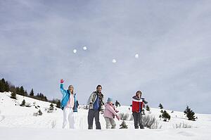 Young Family Throwing Snowballs On Winter Vacation