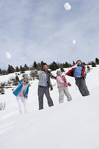 Young Family Throwing Snowballs On Winter Vacation