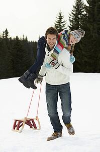 Young Father And Daughter In Snow With Sled