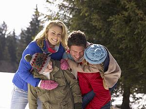 Young Family In Alpine Snow Scene