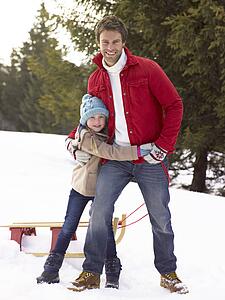 Young Father And Daughter In Snow With Sled