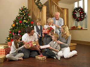 Family exchanging gifts in front of Christmas tree