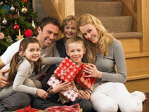 Family with gifts in front of Christmas tree
