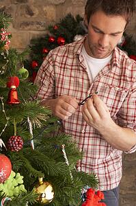Young man fixing Christmas tree lights