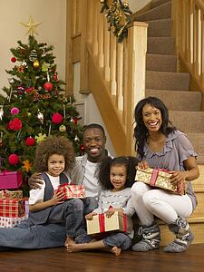 Young African American family with Christmas tree and gifts