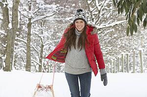 Young woman in snow with sledge