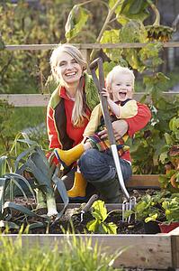 Woman working on allotment with child