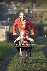 Woman working on allotment with child