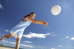 Teenage girl playing beach volleyball
