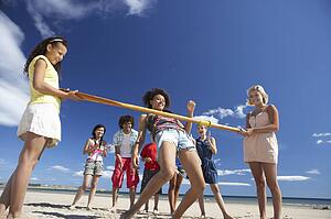 Teenagers doing limbo dance on beach