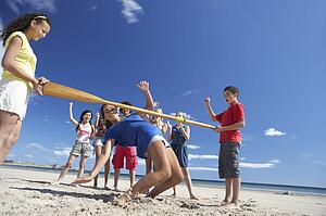 Teenagers doing limbo dance on beach