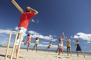 Teenagers playing cricket on beach