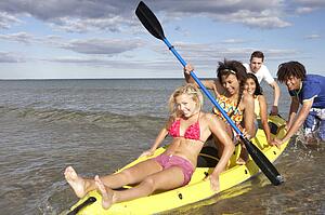 Teenagers in sea with canoe
