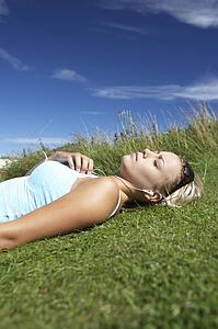Teenage girl lying on grass with mp3 player