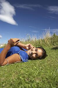 Teenage girl lying on grass with mp3 player