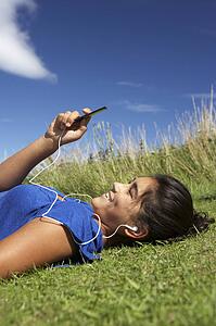 Teenage girl lying on grass with mp3 player