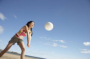 Teenage girl playing beach volleyball