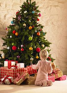 Little girl with parcels round Christmas tree