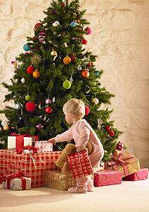 Little girl with parcels round Christmas tree
