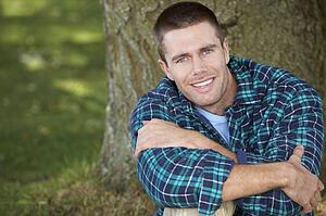 Man sitting against tree trunk