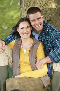 Couple sitting against tree trunk