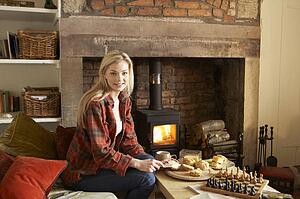 Young woman having tea by fire
