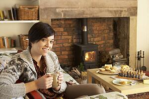Young woman having tea by fire