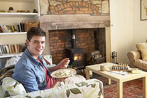Young man eating meal by fire