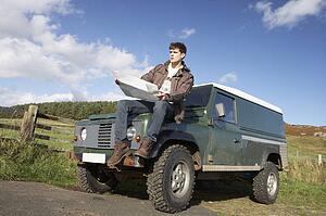 Young man in countryside with SUV