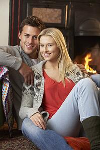 Young couple sitting by open fire