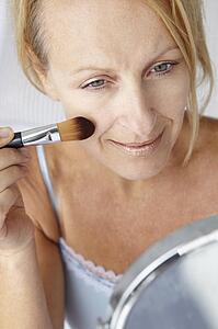 Mid age woman putting on make-up