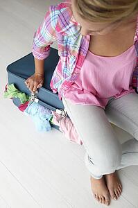 Teenage girl struggling to close suitcase