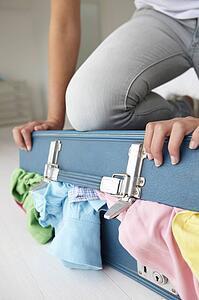 Teenage girl struggling to close suitcase