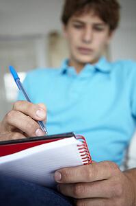 Teenage boy writing in notebook
