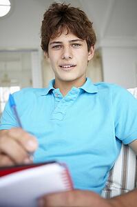 Teenage boy writing in notebook