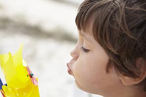 Young boy blowing on windmill