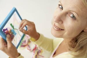 Mid age woman doing cross stitch