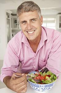 Mid age man eating salad